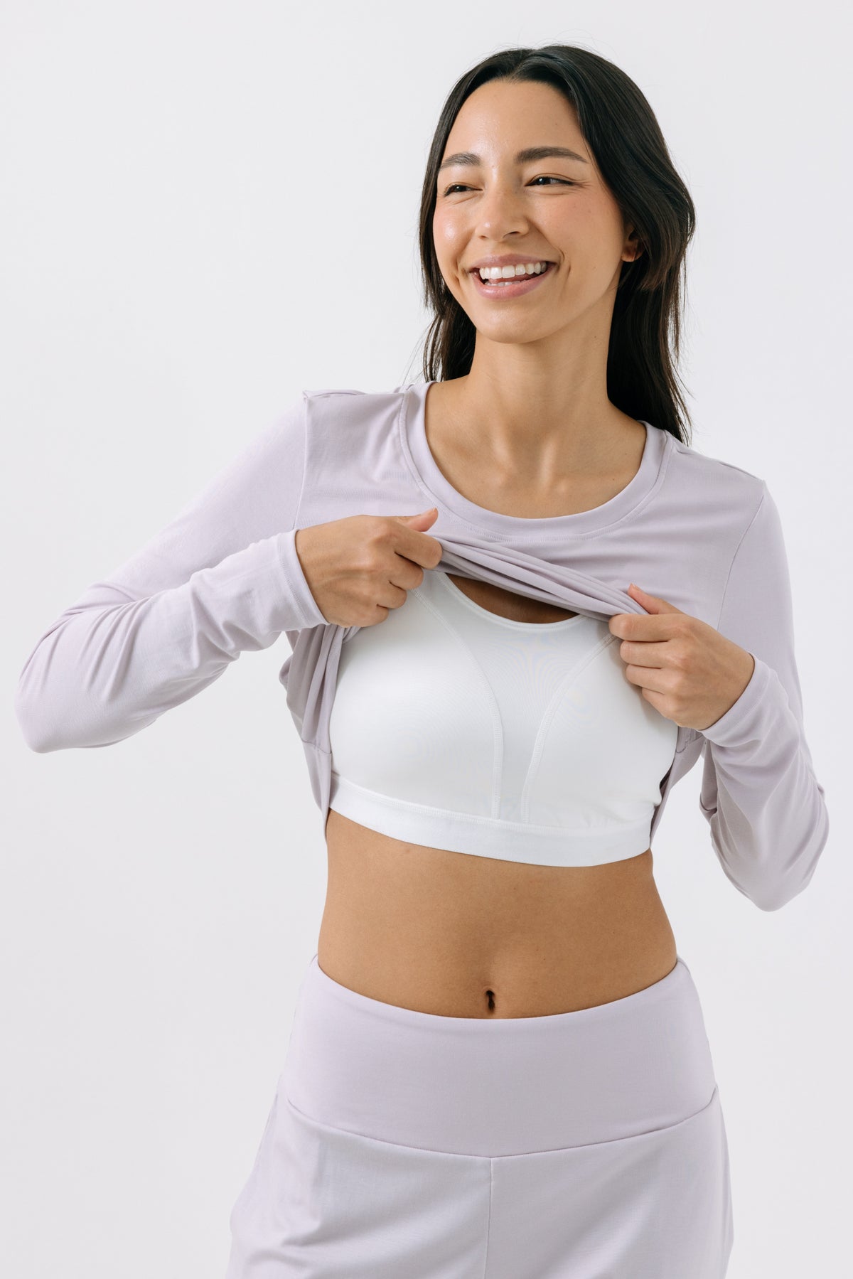 A woman wearing a lavender, long-sleeve pajama t-shirt showing a built-in bra underneath on a white, studio background.