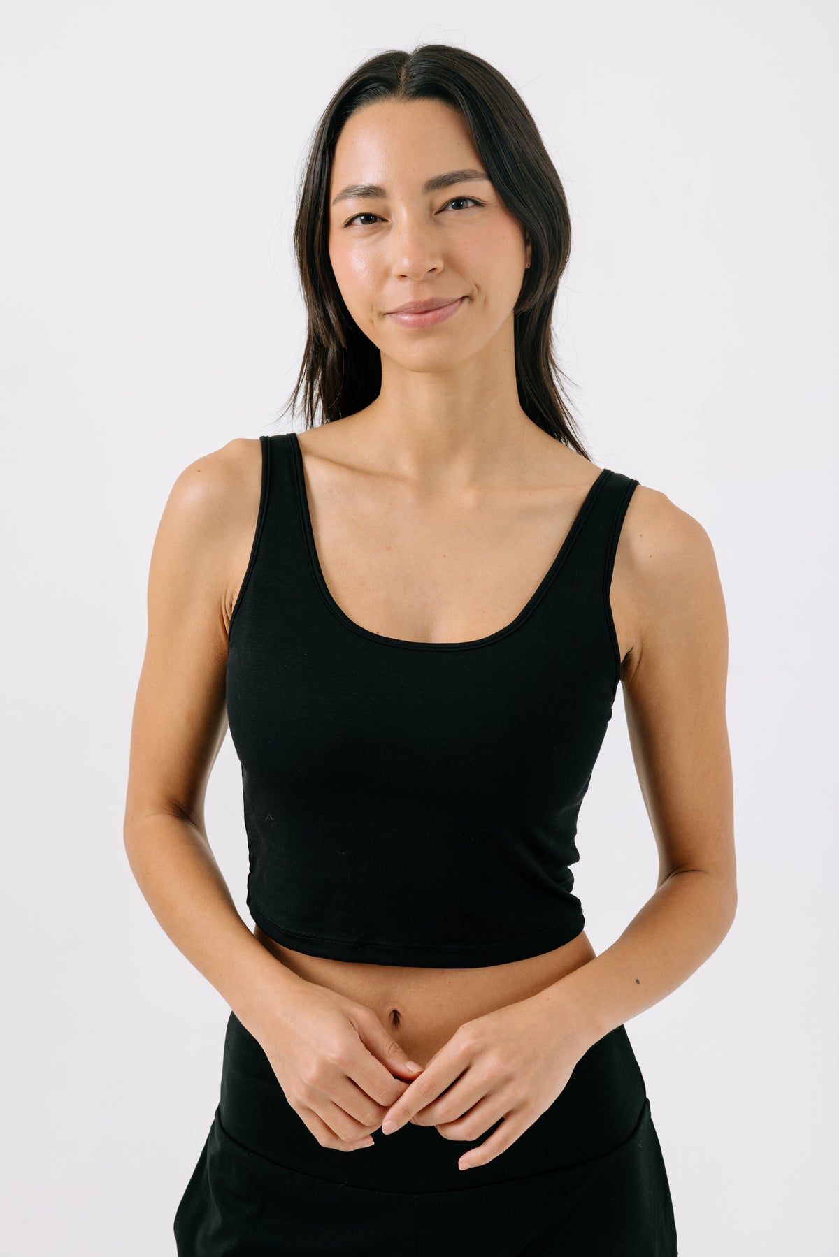 Woman wearing a black pajama crop top on a white studio background.