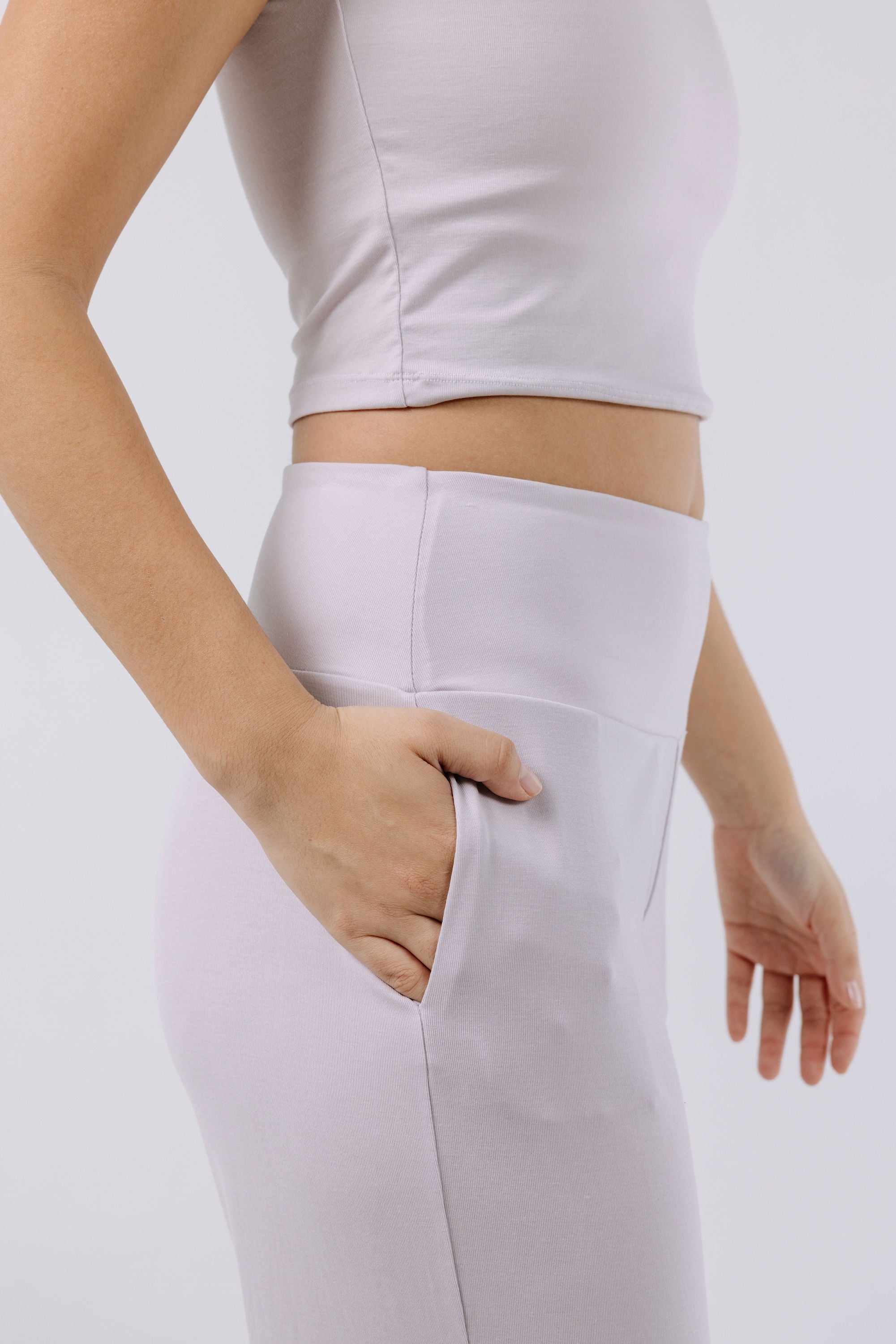 Person wearing a lavender pajama crop top and pants on a light gray background.