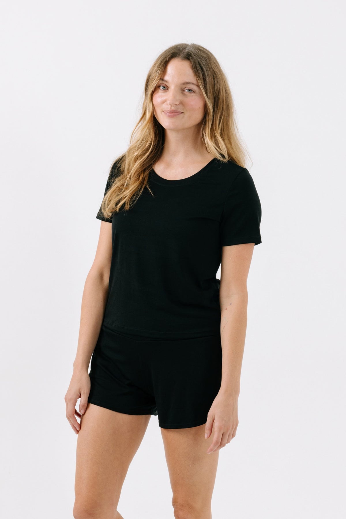 Woman wearing a black pajama t-shirt on a white studio background.