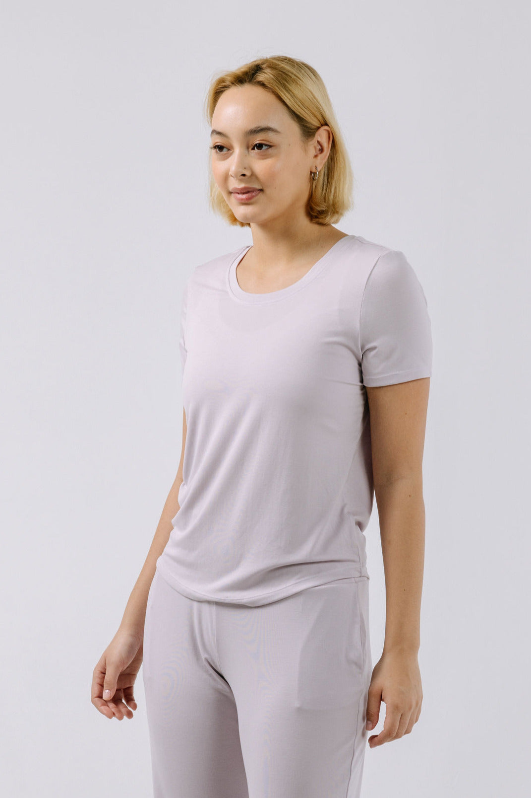 Woman wearing a lavender pajama t-shirt and pants on a white background.