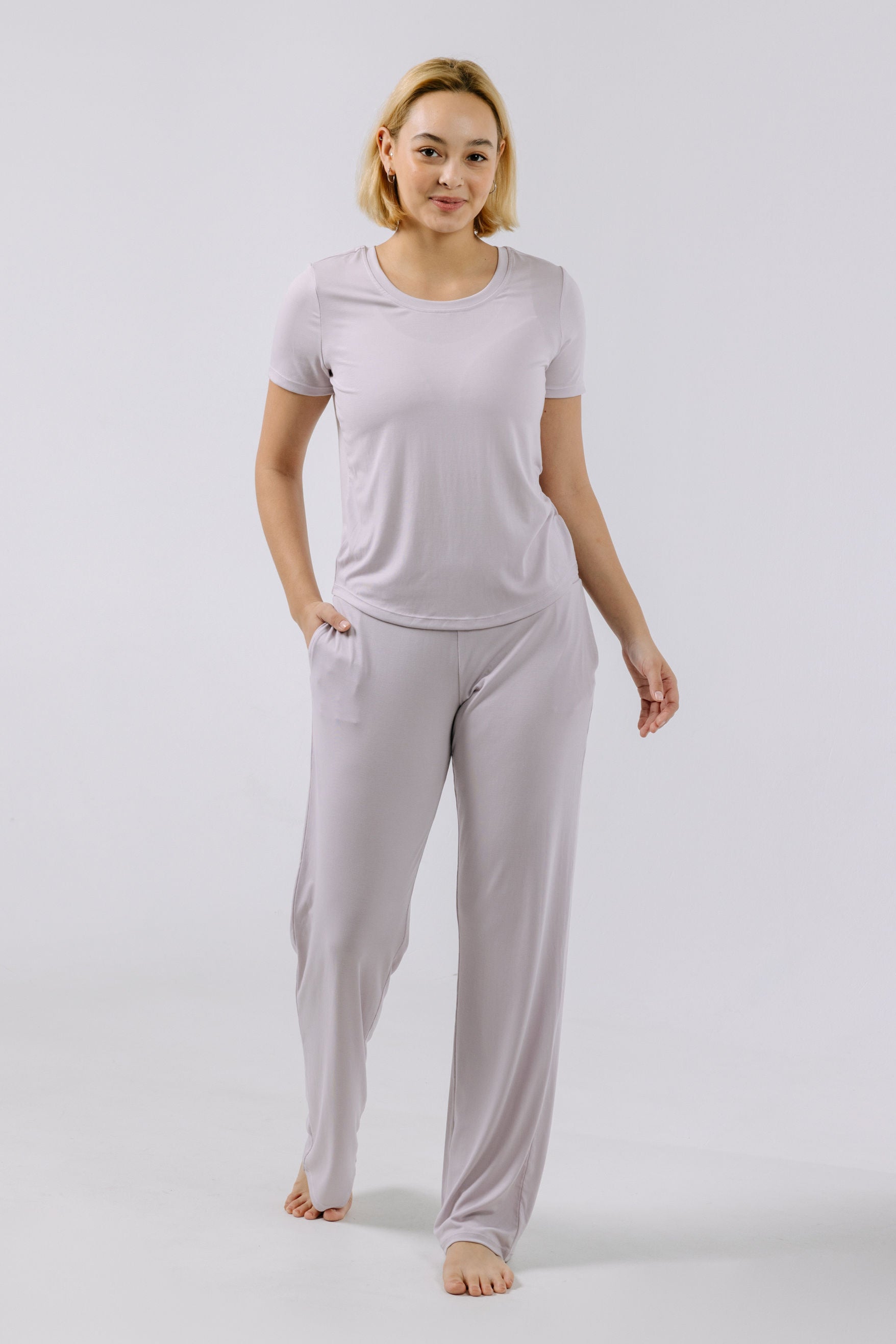 Woman wearing a lavender pajama t-shirt and pants on a white background.