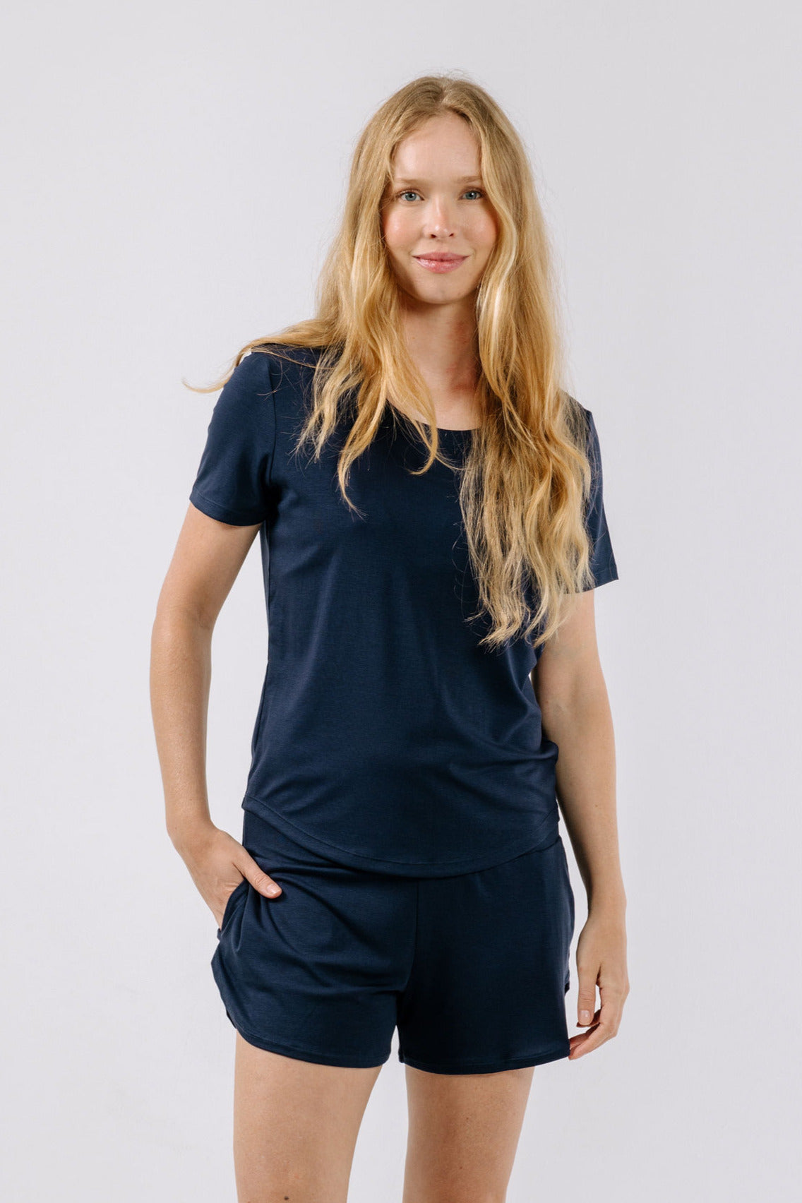 Woman wearing a navy blue matching pajama t-shirt and shorts on a white background.