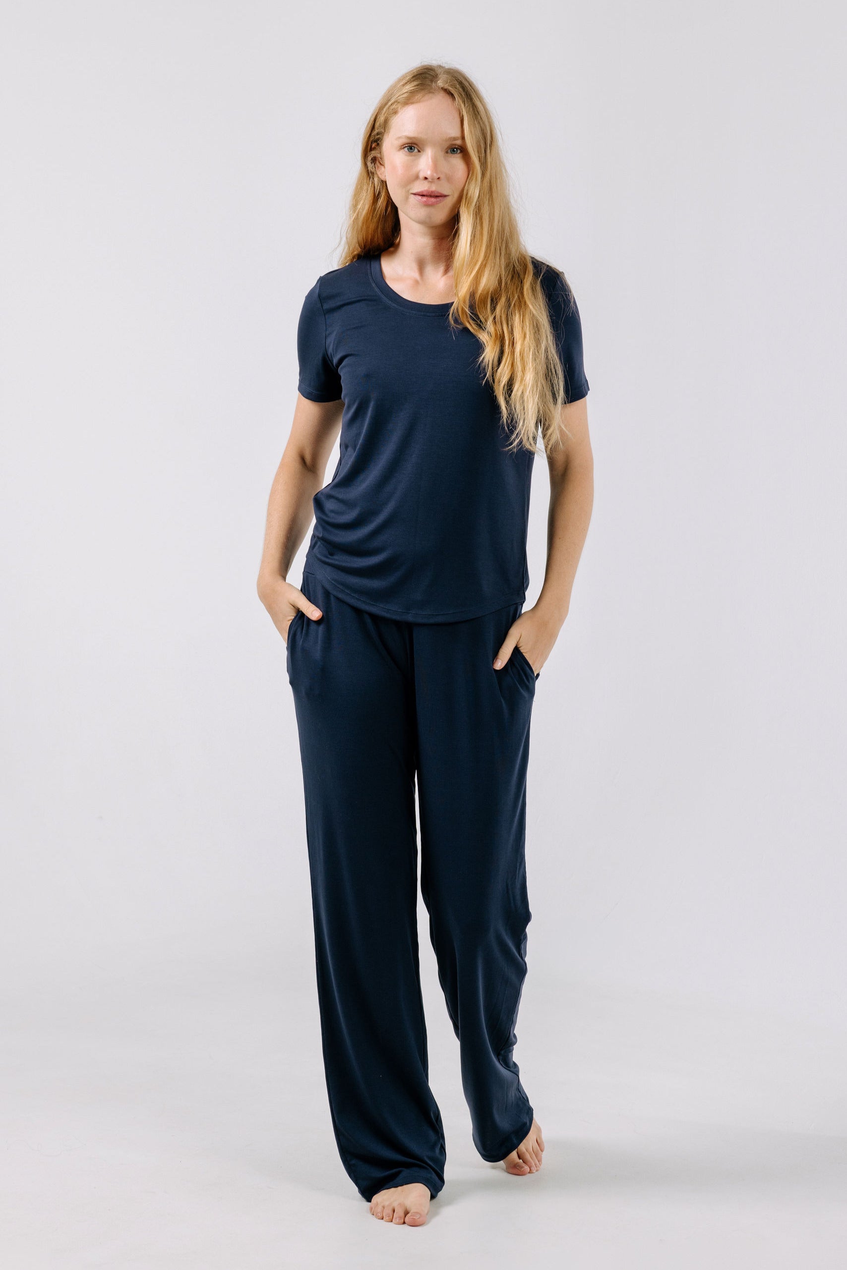 Woman wearing a navy blue pajama t-shirt and pants on a white background.