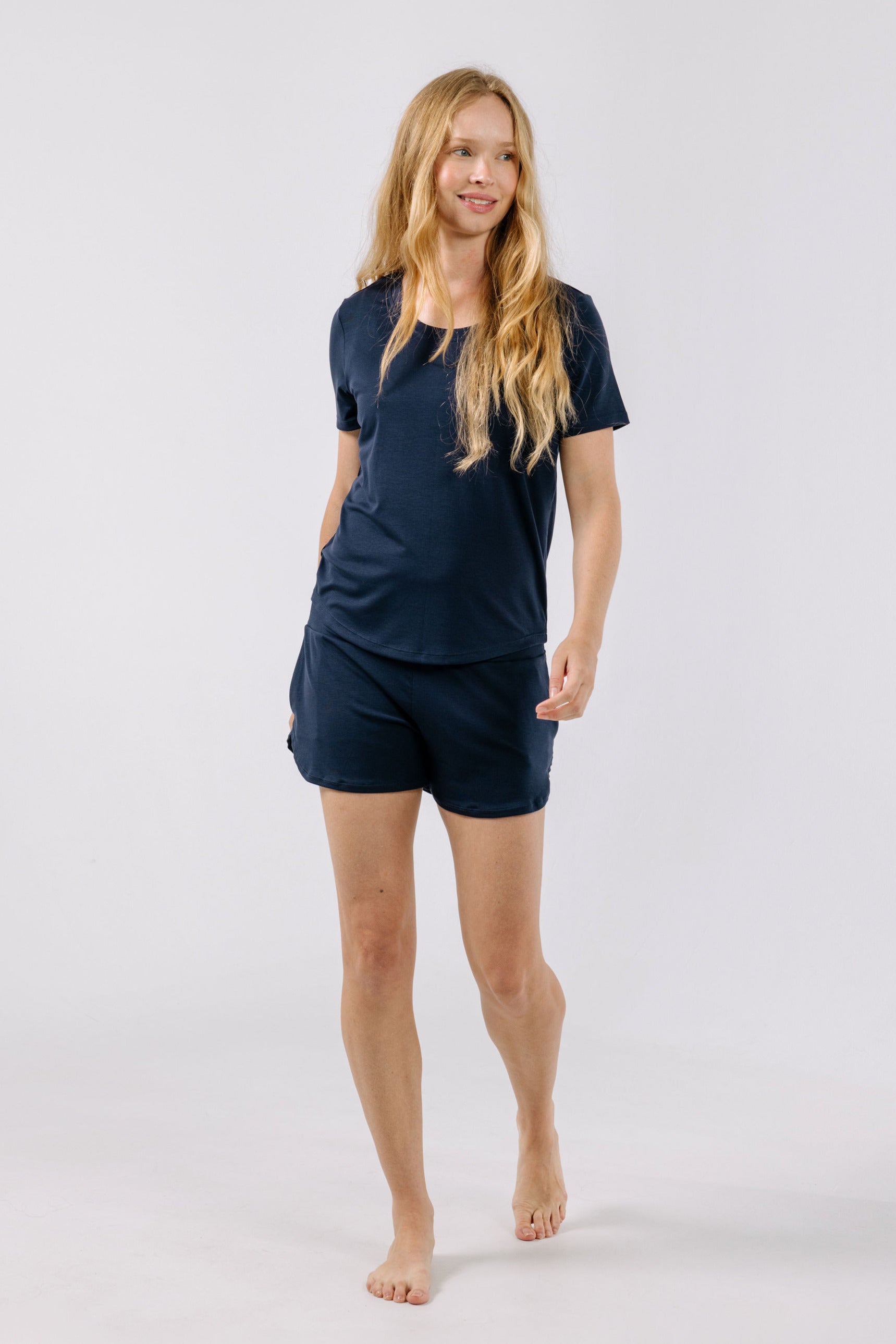 Woman wearing a navy blue pajama t-shirt and shorts on a white background.