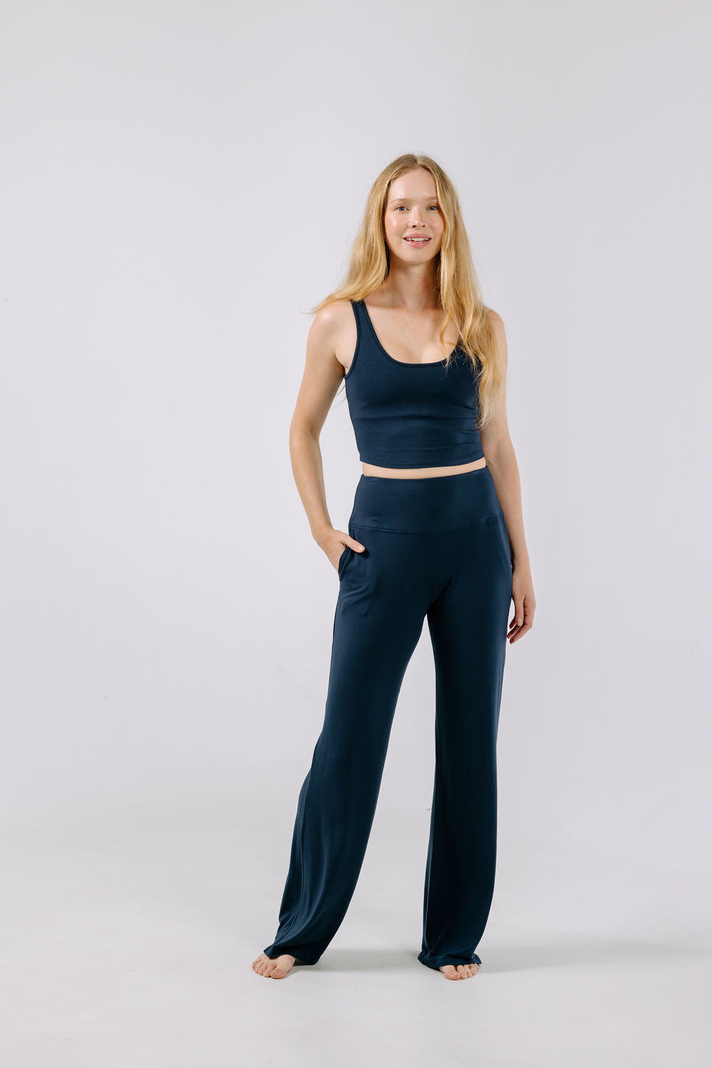 Woman wearing a navy pajama crop top and matching pajama pants on a white background.