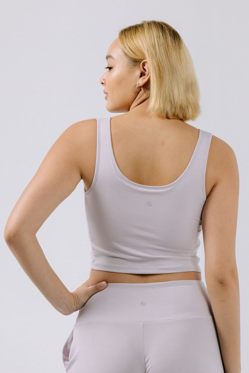 Woman wearing a lavender pajama crop top and pants on a white background.