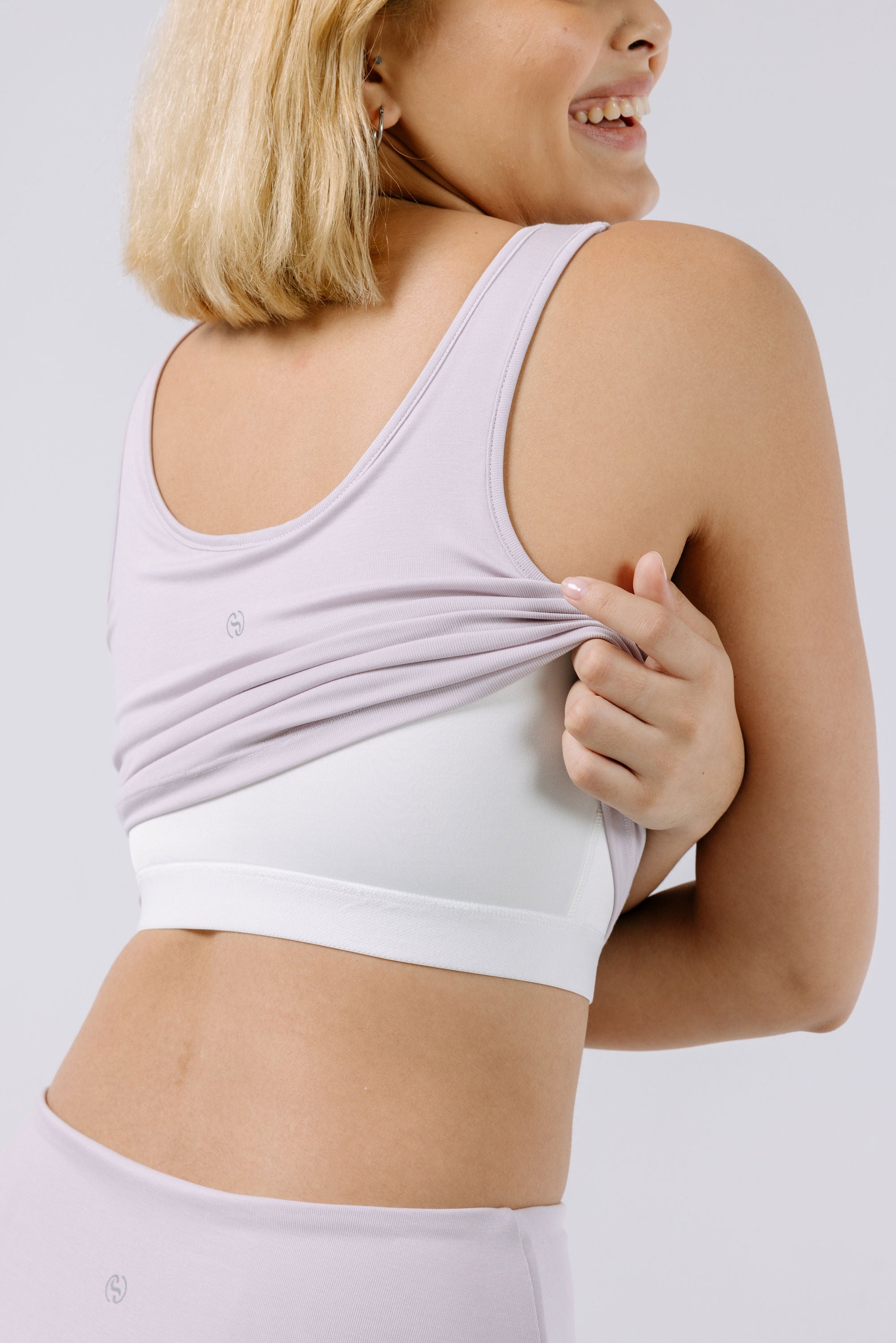 Woman wearing a lavender pajama crop top with a built-in bra on a plain background.