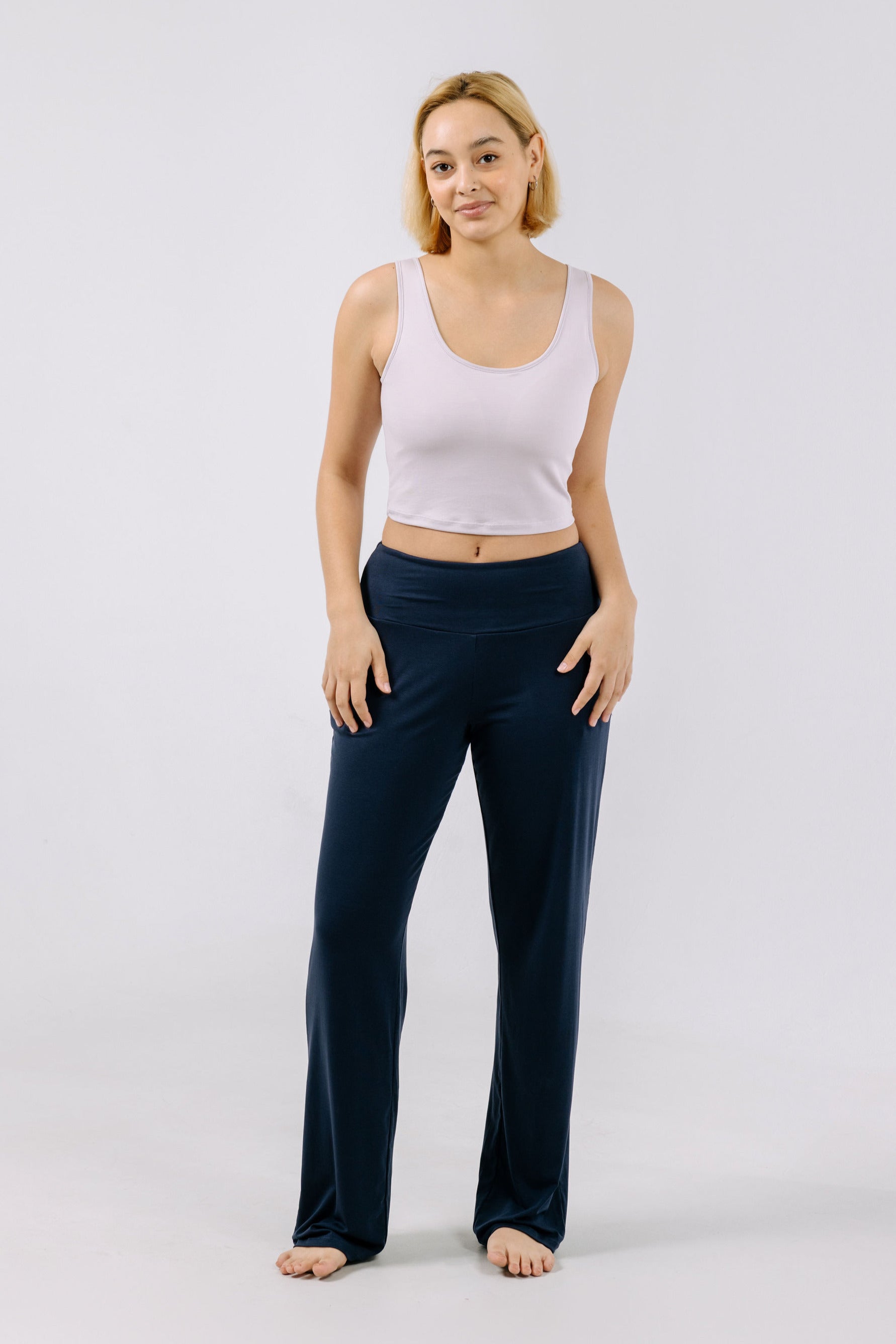 Woman wearing a lavender pajama crop top and navy pants against a white background.