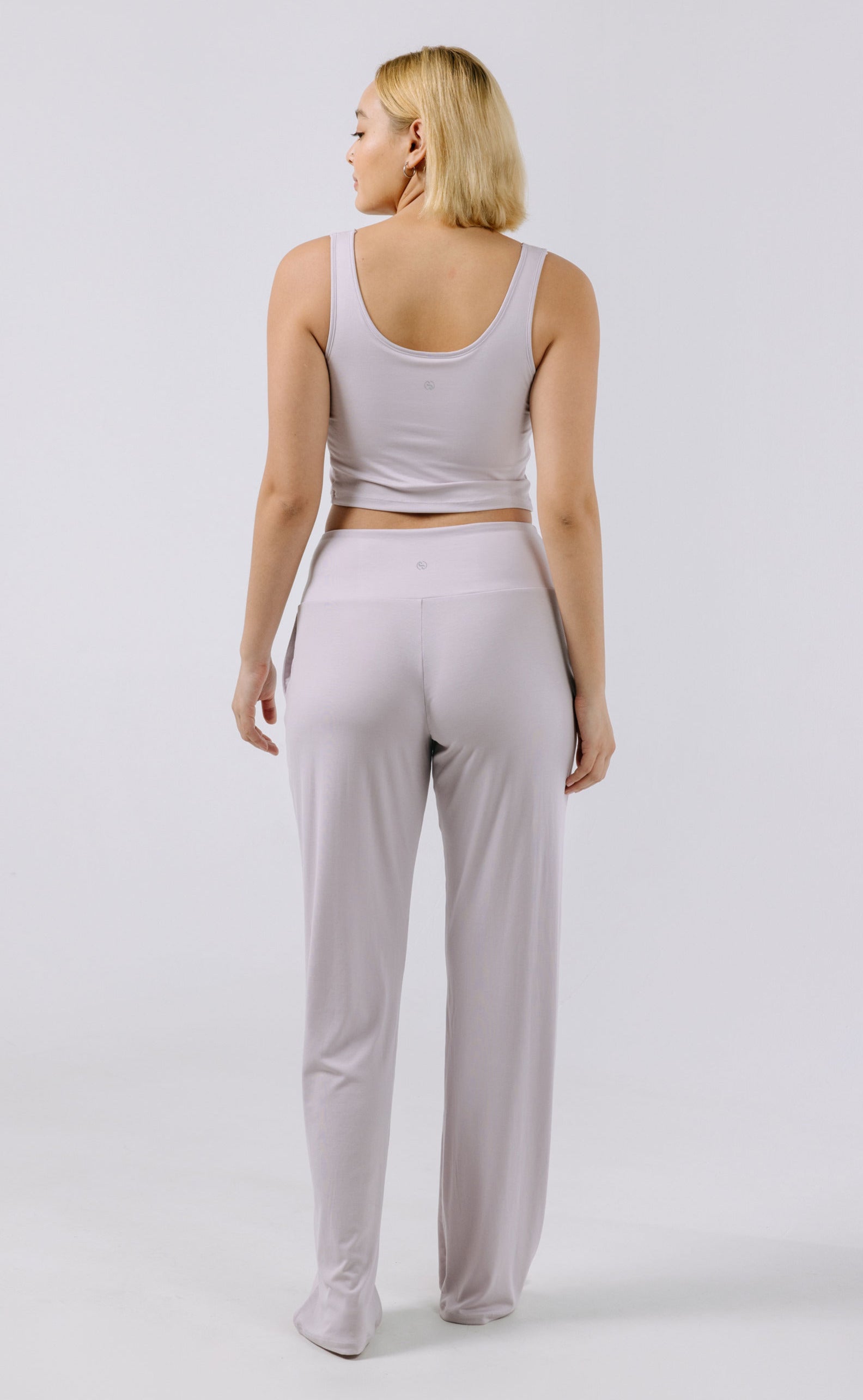 Woman wearing a lavender pajama tank top and pants on a white background.