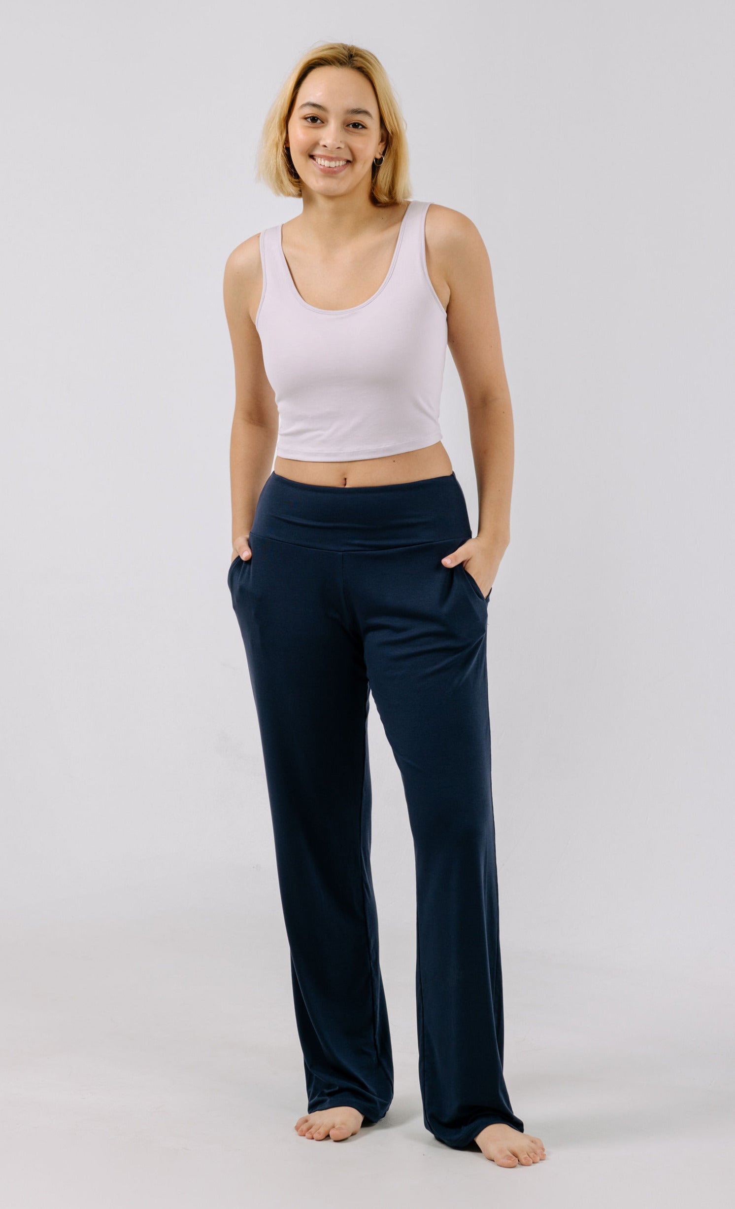 Woman wearing a lavender pajama crop top and navy pajama pants on a light gray background.