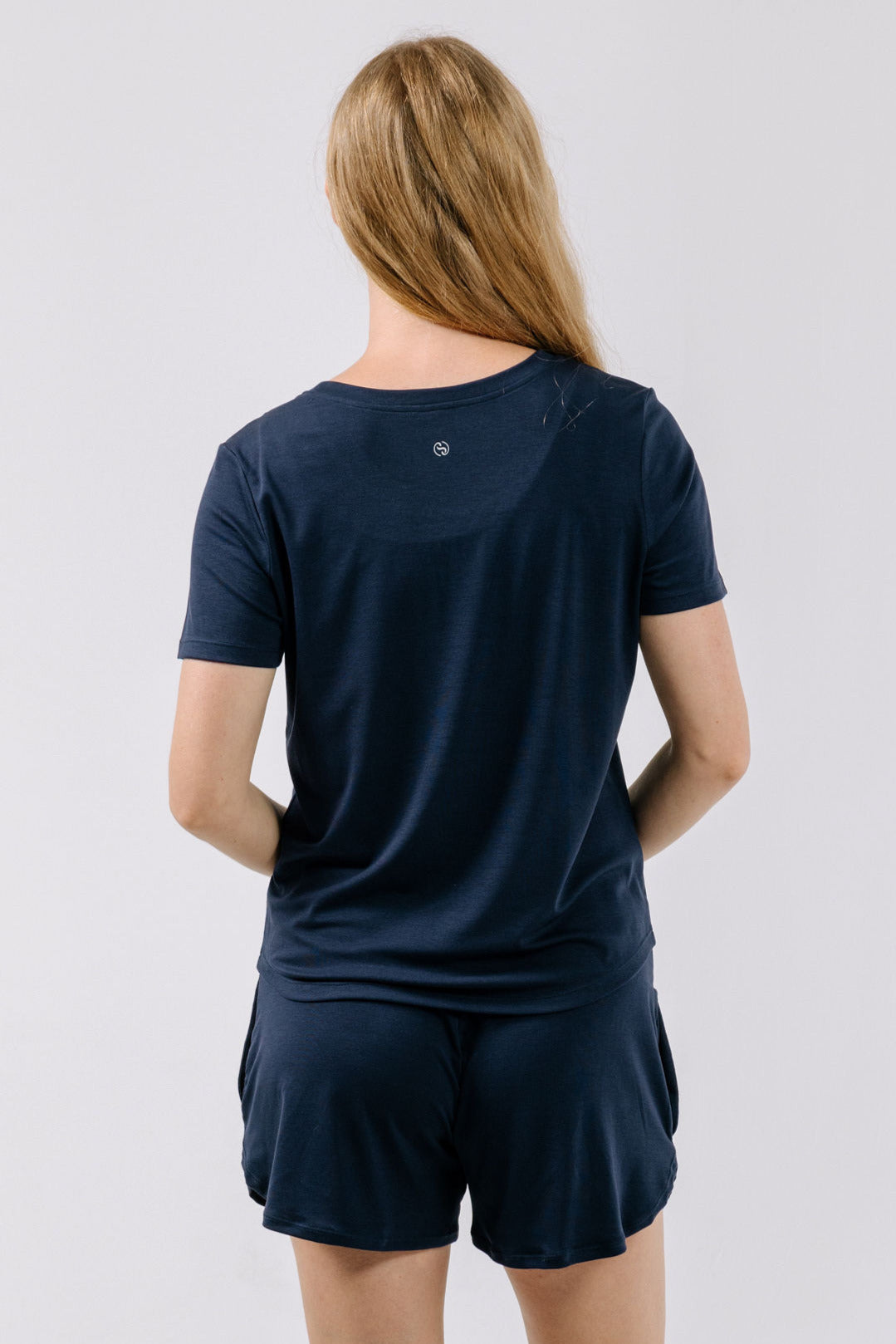 Person wearing a navy blue pajama t-shirt and shorts on a white background.