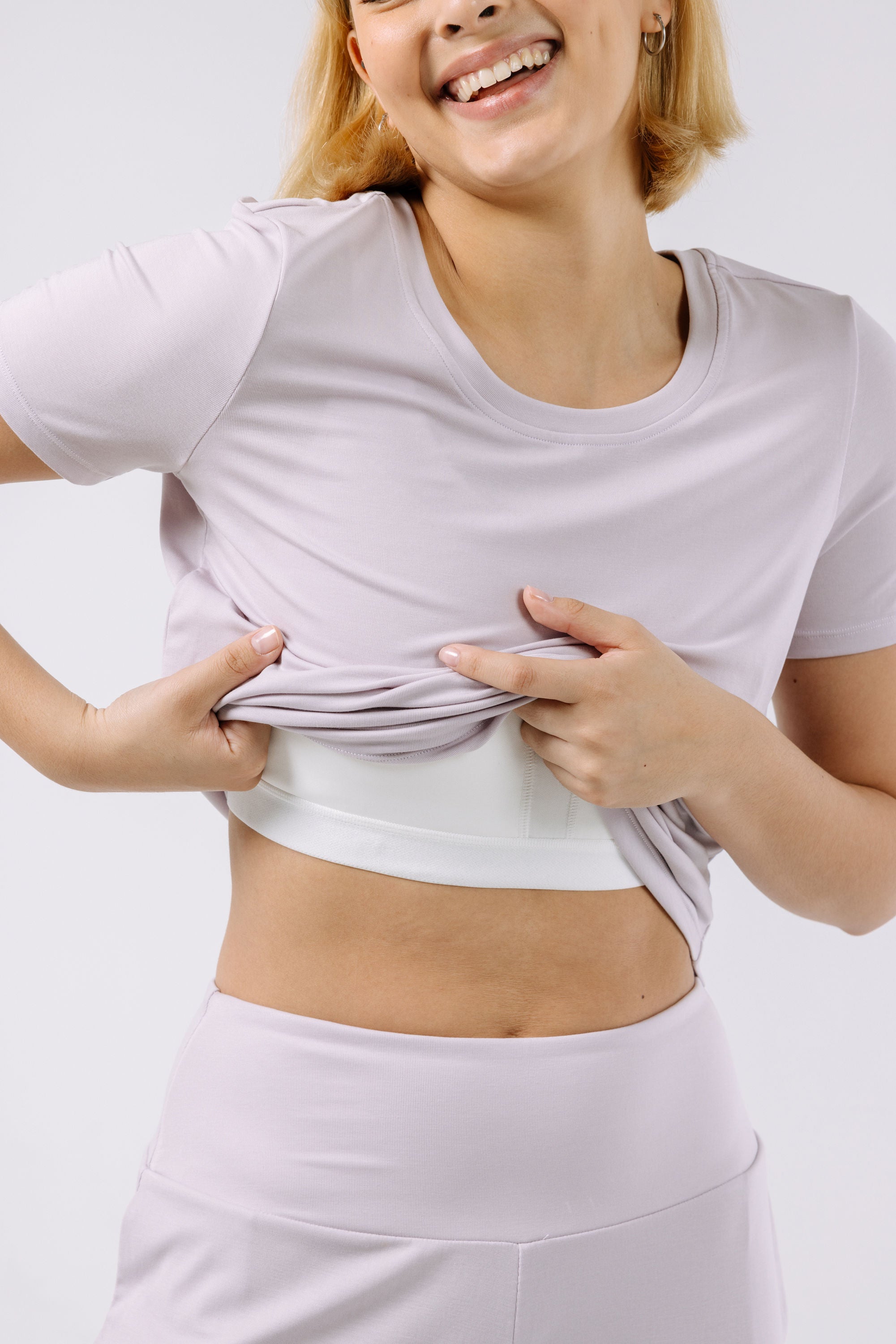 Woman wearing a lavender pajama t-shirt with a built-in bra on a white background.