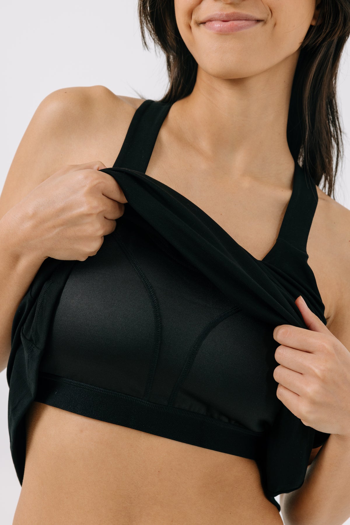 A woman showing a built-in bra underneath a black racerback pajama dress on a white background.