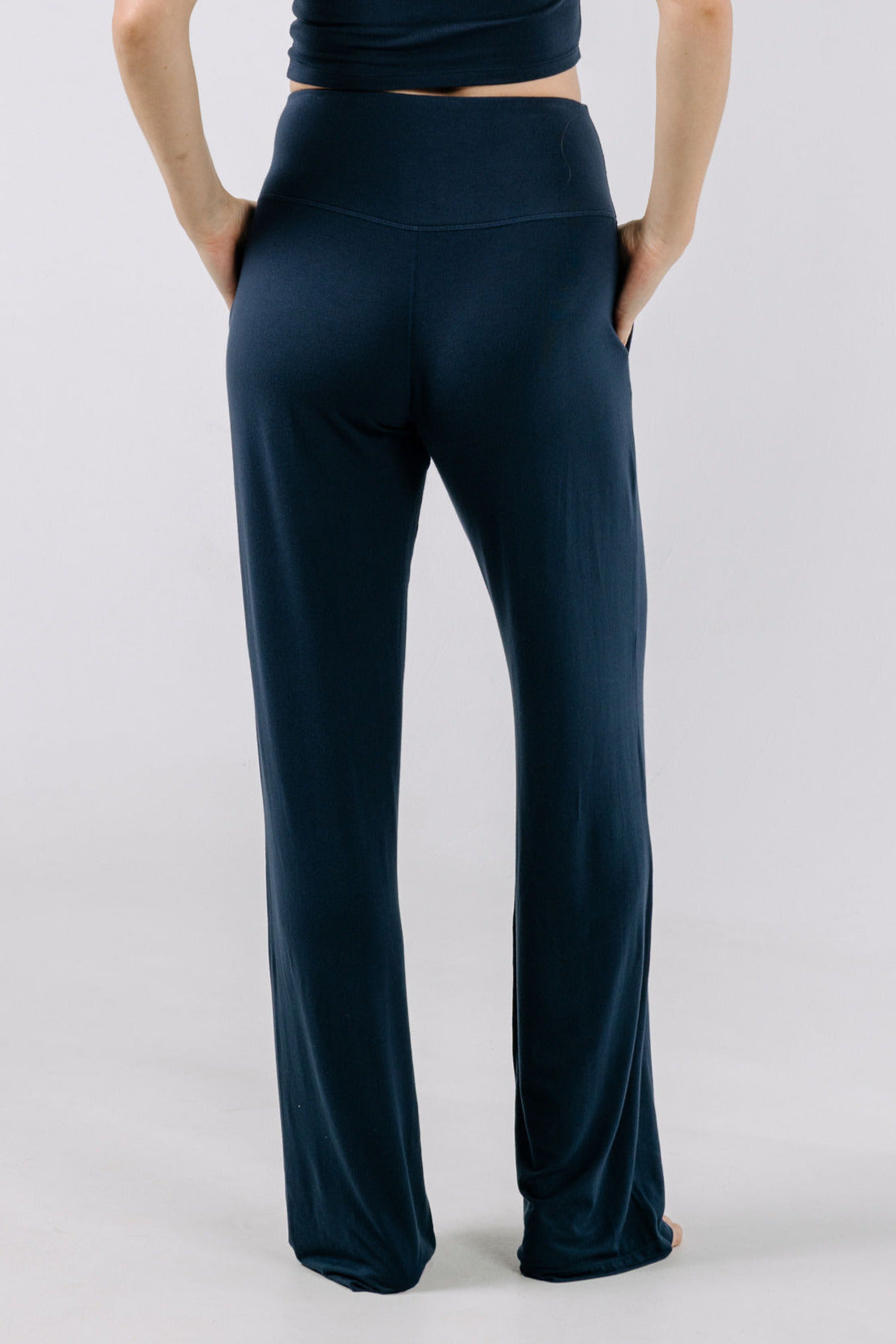 Person wearing navy blue pajama pants on a light gray background.