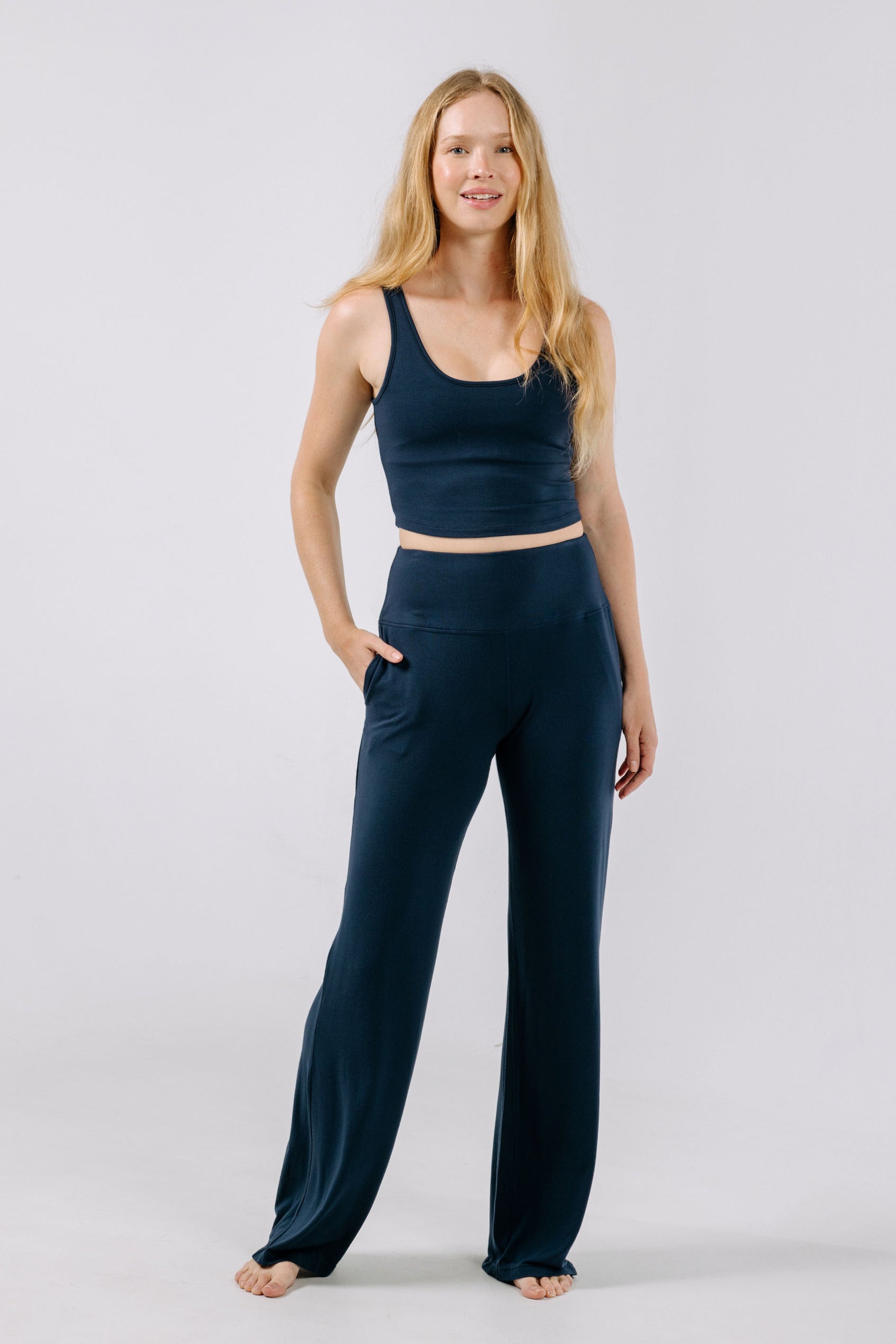 Woman wearing a navy blue pajama crop top and pants on a white background.