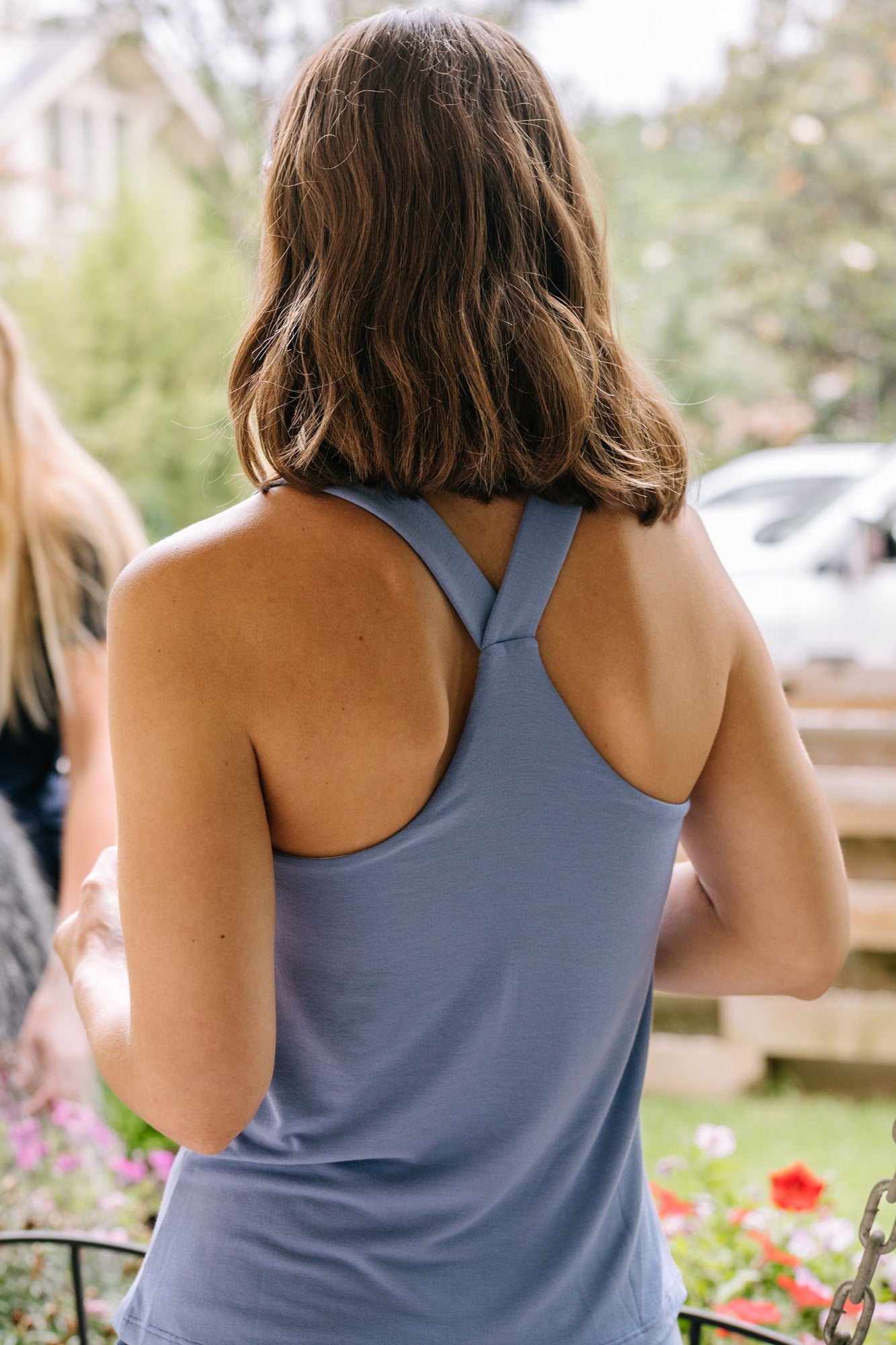 Woman wearing a periwinkle racerback pajama tank top with a blurred outdoor background.
